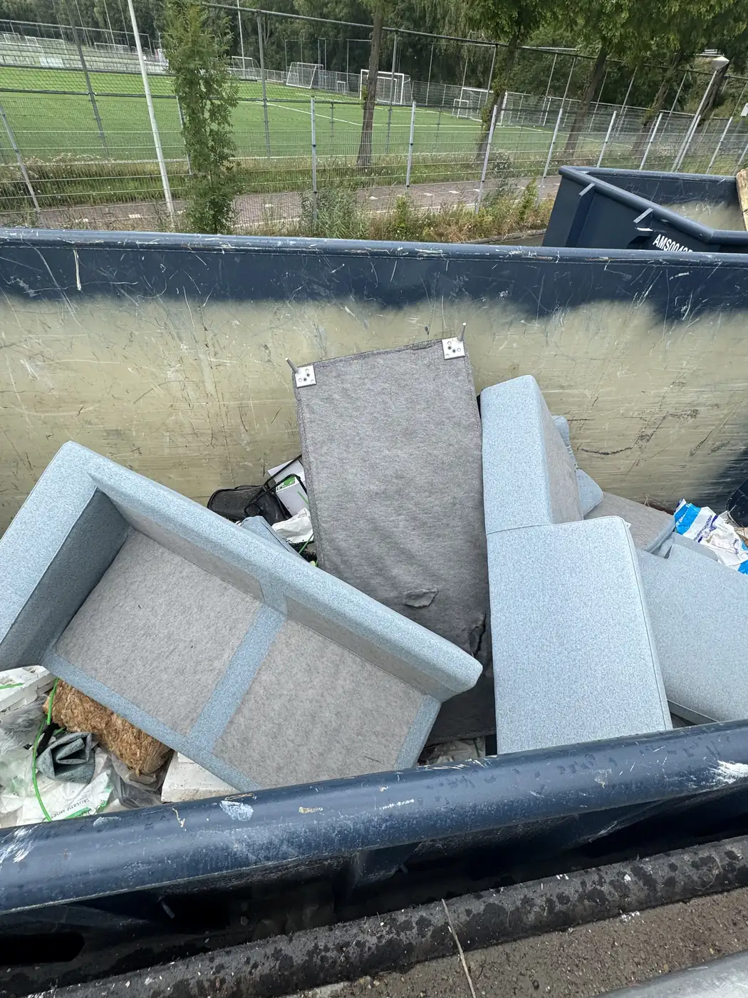 Gedemonteerde grijze bank in de container, klaar voor verwerking
